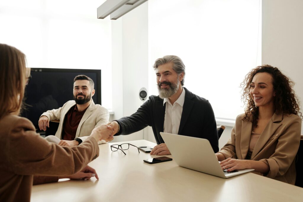 pexels-photo-4342126-4342126 A group of business professionals shake hands during a meeting in a modern office setting.