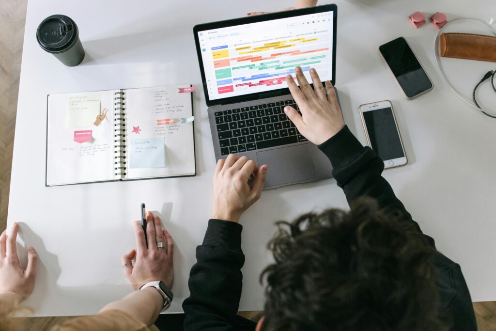 pexels-photo-7213549-7213549 Two people collaborating on a laptop and planner at a vibrant modern office desk.